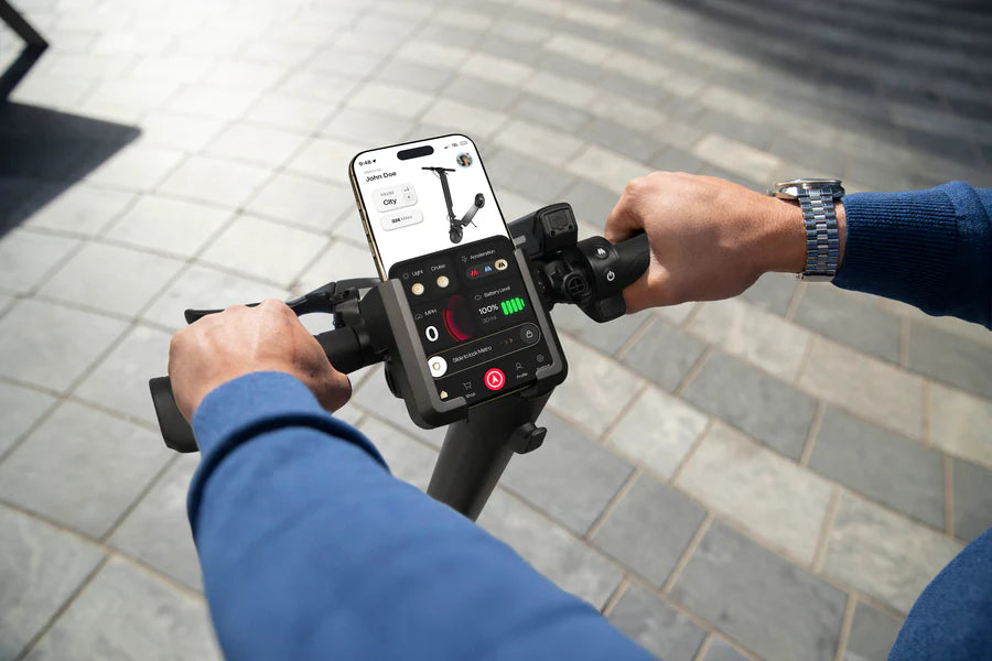 Using a smartphone app on an metro america electric scooter with a watch visible.
